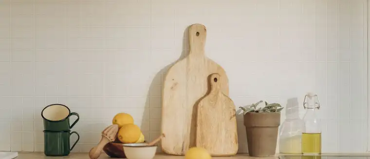 Lemons, a glass bottle, mugs and cutting boards on a bright kitchen counter