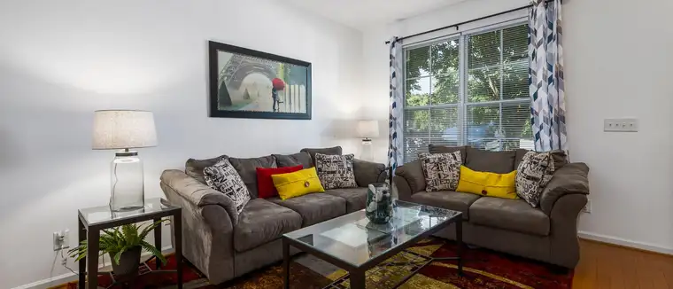 Bright living room with gray sofas, throw pillows, a patterned rug and curtains