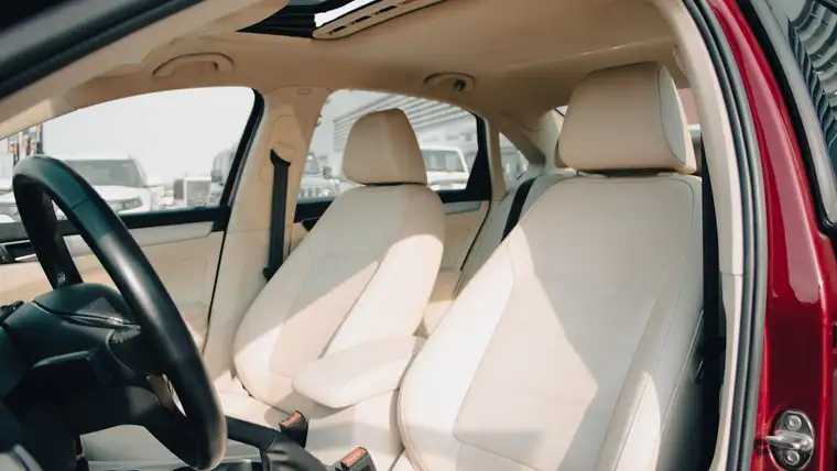 Cream leather front seats and steering wheel inside a car with an open door