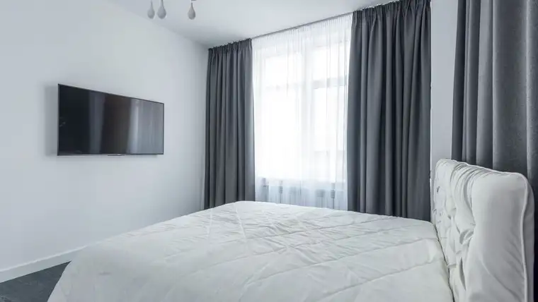 Long gray curtains framing a bright window in a white bedroom