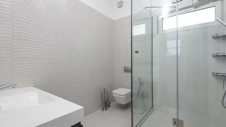 Frameless glass shower enclosure in a bright white bathroom
