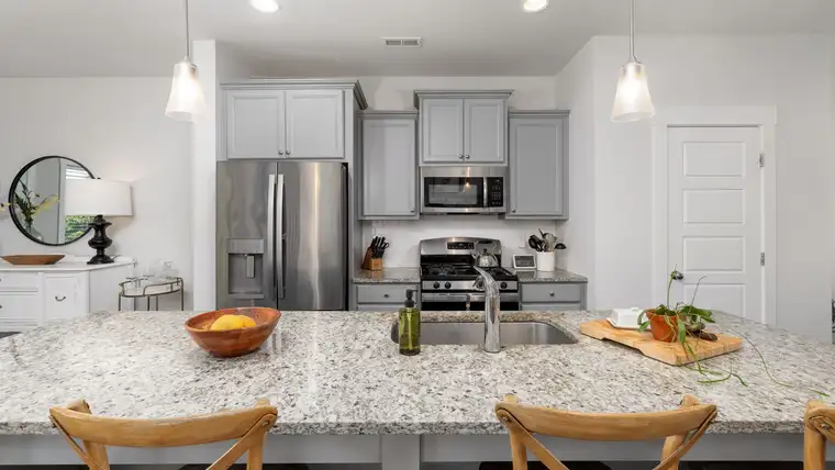 Speckled granite kitchen island with sink, fruit bowl and wooden bar stools