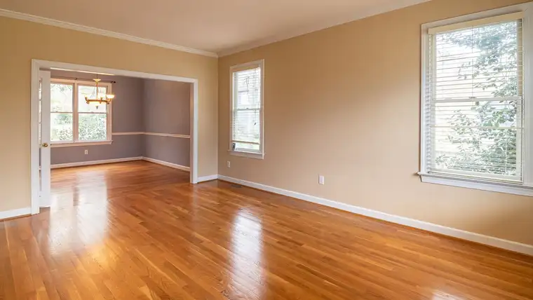 Bright empty room with glossy honey-colored hardwood floors and white trim