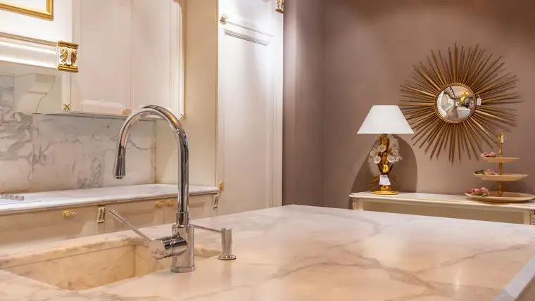 Veined white marble countertop and backsplash with a chrome kitchen faucet