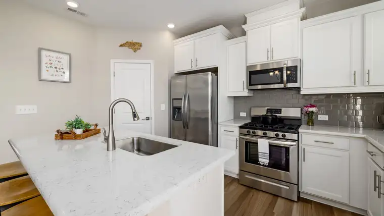 White kitchen island with a smooth veined countertop and undermount sink