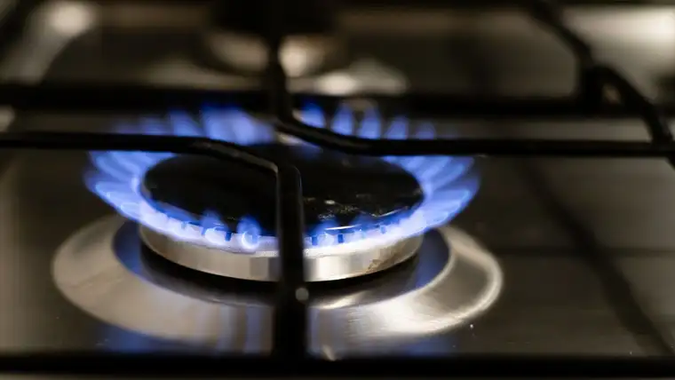 Blue gas flame on a stovetop burner beneath black cast iron grates