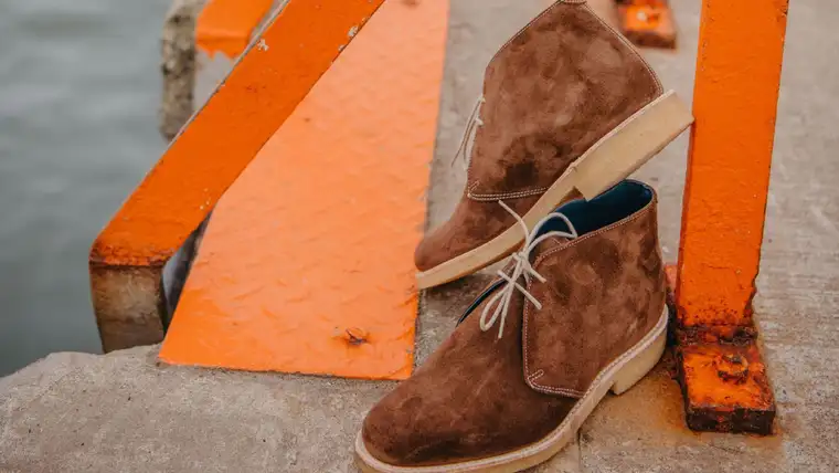 Pair of brown suede chukka boots with crepe soles on a concrete step