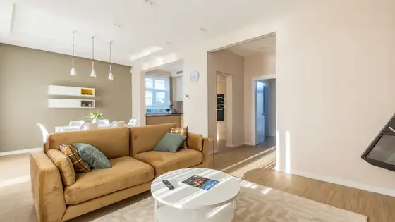 Sunny, tidy living room with a mustard sofa, white coffee table and light floors