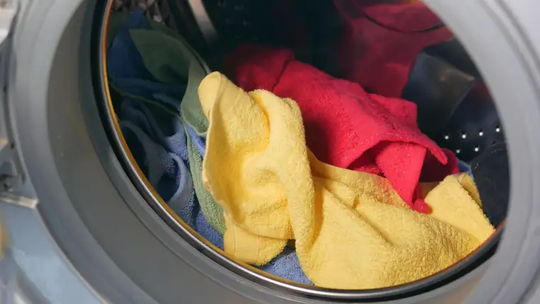 Mixed red, yellow, blue and green towels tumbled together inside a washing machine drum