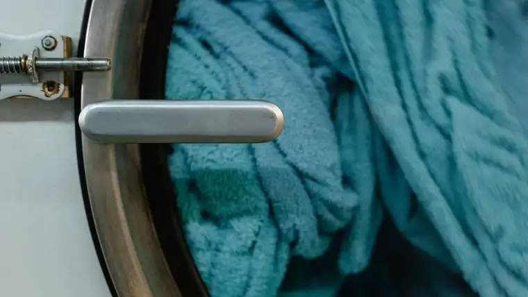 Teal bath towels packed inside a front-loading washing machine drum