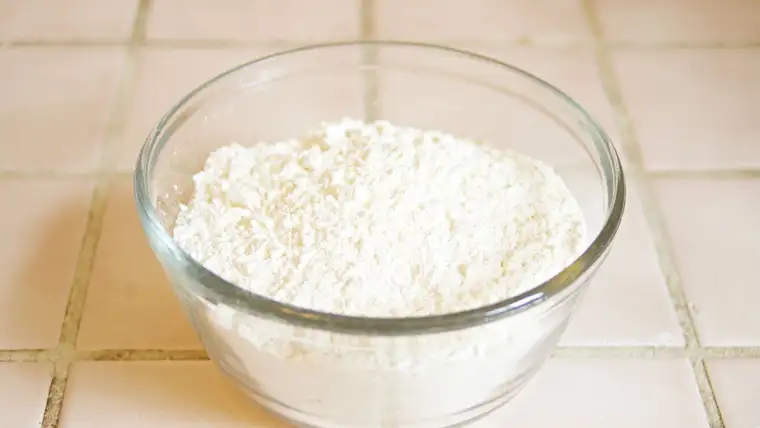 Glass bowl filled with fine white cornstarch powder on a tiled counter