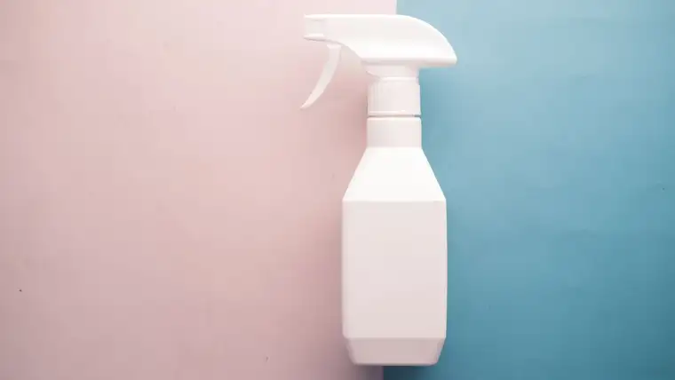 Plain white unlabeled trigger spray bottle on a pink and blue background