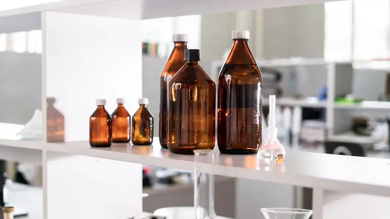 Amber brown glass bottles of various sizes lined up on a white shelf
