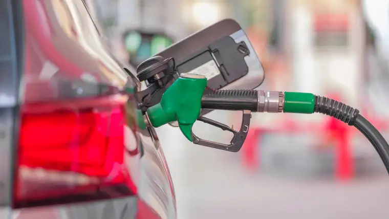 Green fuel pump nozzle inserted into a car's open gas tank