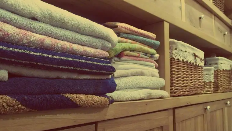 Stacks of folded towels and wicker baskets on wooden closet shelves