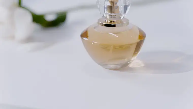 Round glass perfume bottle with amber fragrance on a white surface