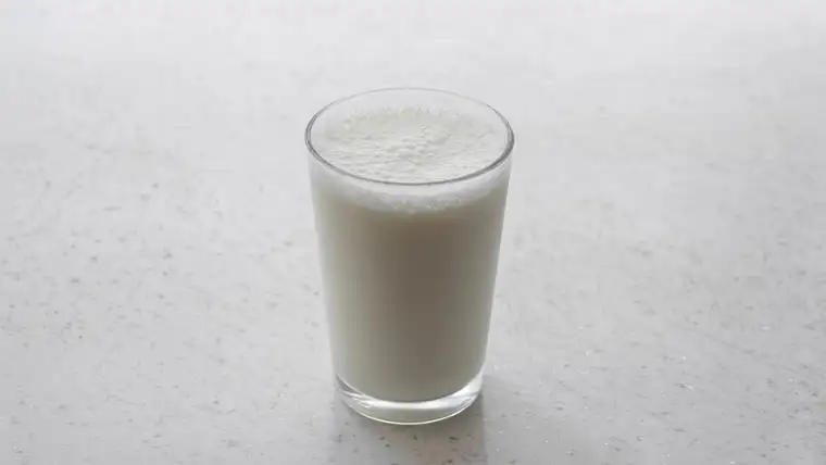 Single glass of milk standing on a pale gray countertop