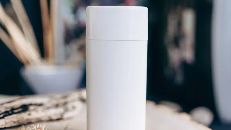 Plain white unlabeled deodorant stick standing on a slice of wood
