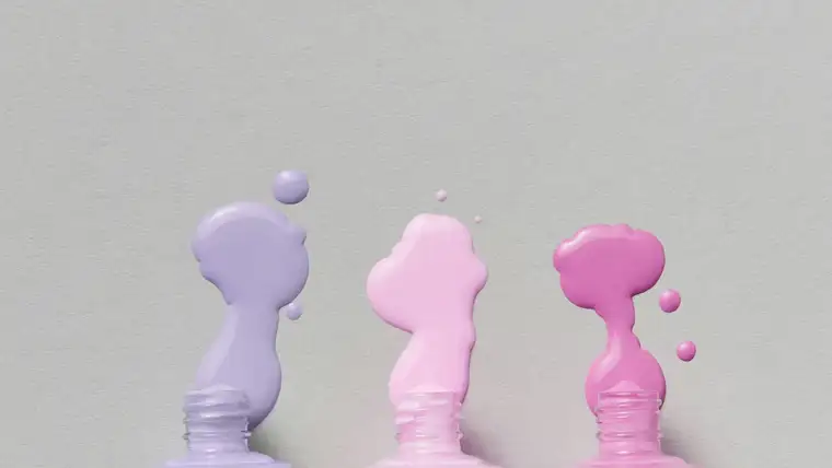Three tipped nail polish bottles spilling lavender and pink polish on gray